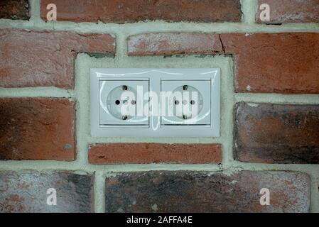 white double socket is built into the brick wall Stock Photo