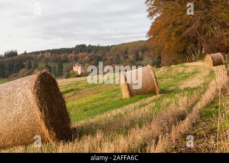 A View of Craigievar Castle in Autumn Sunshine with Straw Bales in a Stubble Field in the Foreground Stock Photo
