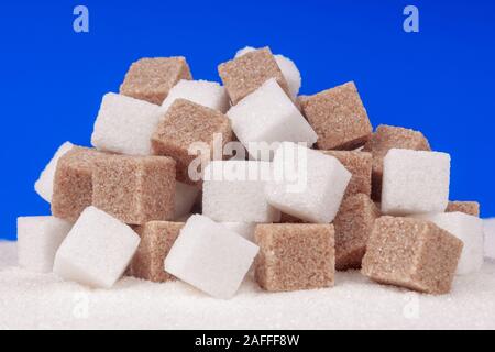 Heap of cane sugar and white sugar on a blue background Stock Photo
