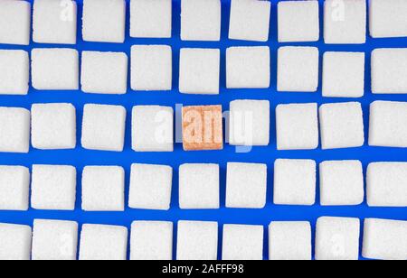 Many cubes of white sugar with one other. Concept not like everyone on blue background top view Stock Photo