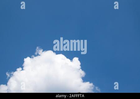 Large fluffy clouds against a blue sky. Sunny weather, summer. Bright blue sky sunny day. Blue sky with cumulus cottony clouds at the bottom of the fr Stock Photo