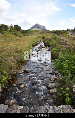 Under old stone bridge runs river with enchanted waters Beginner climbers start ascents of the Cuillin mountains from Sligachan located at a junction Stock Photo