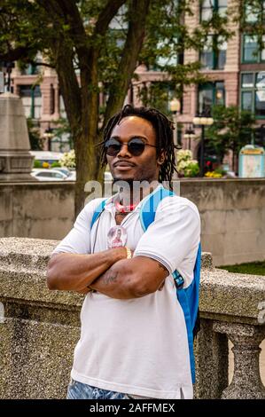 Chicago, Illinois-August 21, 2019: Young black man in sunglasses is smiling and posing with crossed arms in Grant Park. Stock Photo