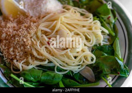 Close-up on capellini angel hair pasta with virgin olive oil, spinach, fresh lemon, chili flakes, garlic and  toasted bread crumbs, dinner angle view Stock Photo