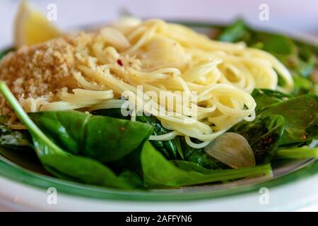 Close-up on capellini angel hair pasta with virgin olive oil, spinach, fresh lemon, chili flakes, garlic and  toasted bread crumbs, side view Stock Photo