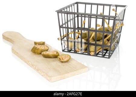 Group of lot of whole four slices of pickled green caper in black plastic basket on wooden cutting board isolated on white background Stock Photo