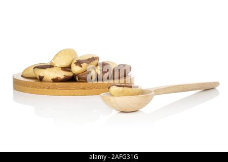Lot of whole brazil brown nut on round bamboo coaster with wooden scoop isolated on white background Stock Photo