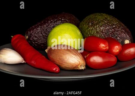 Lot of whole ingredient guacamole on gray ceramic plate isolated on black glass Stock Photo