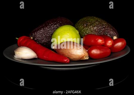 Lot of whole ingredient guacamole on gray ceramic plate isolated on black glass Stock Photo