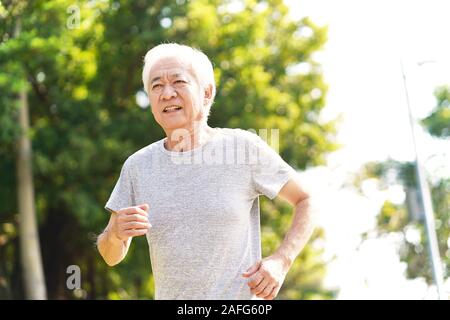 senior asian man jogging running outdoors in park Stock Photo