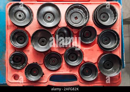 Red Box with a set of removable caps for oil filters of different sizes and diameters for the safe removal of old parts in a vehicle repair workshop. Stock Photo
