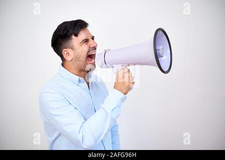Studio shoot of young entrepreneur making announcement and shouting in megaphone Stock Photo