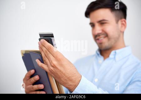 Smiling young businessman attaching credit card reader to digital tablet, selective focus Stock Photo