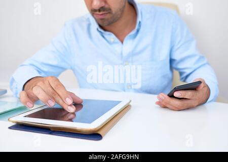 Close-up image of businessman zooming in photo on tablet computer when working at his desk Stock Photo