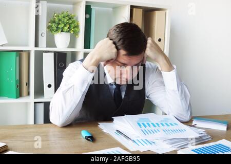 Sad businessman with business report and stack of papers in the office. Stock Photo