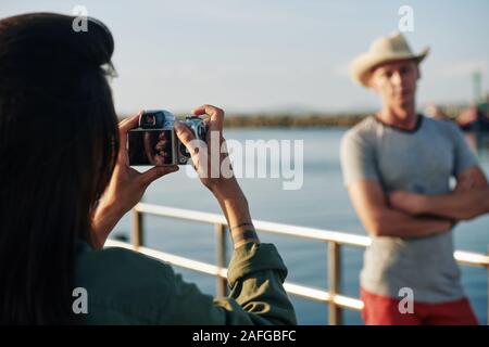 Cheerful woman using digital camera when photographing her husband during short trip, selective focus Stock Photo