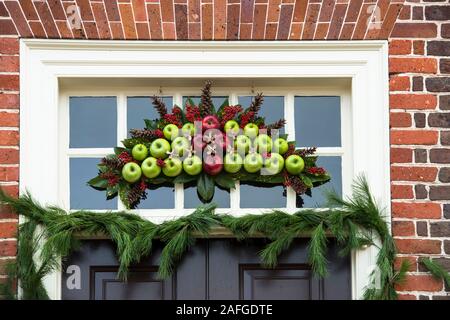 Christmas wreath and transom decoration made of magnolia leaves, evergreen and massed red and green apples. Colonial Williamsburg. Evergreen garland. Stock Photo