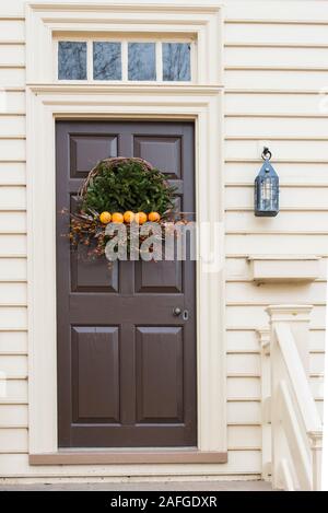 Evergreen and twig.stick Christmas wreath on brown door on colonial porch in the historic area. Colonial Williamsburg. Five oranges in a line. Stock Photo