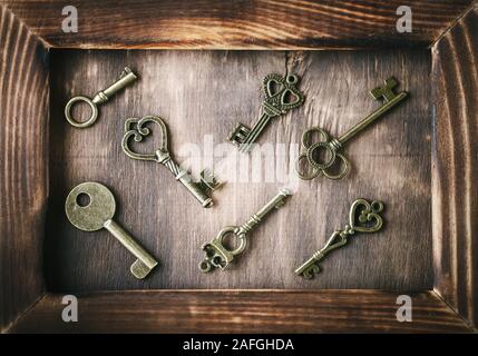 Many ancient keys lie on a wooden table. Stock Photo