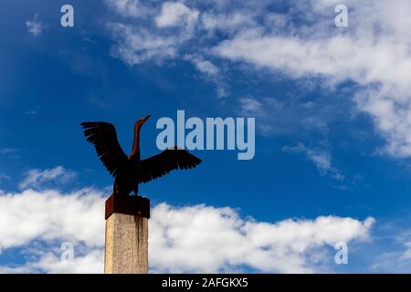 An outdoor sculpture of a rusted metal bird sits on top of a wooden pole at Port Germein jetty in South Australia Stock Photo