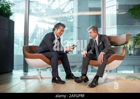 Businessmen using smartphone in office Stock Photo