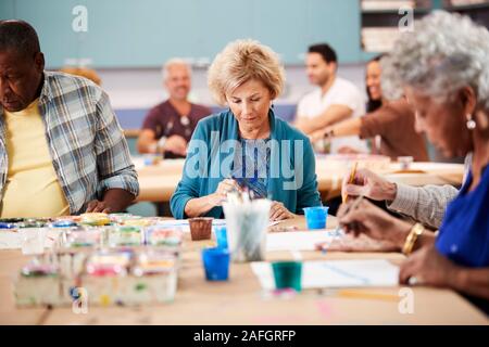 Group Of Retired Seniors Attending Art Class In Community Centre With Teacher Stock Photo