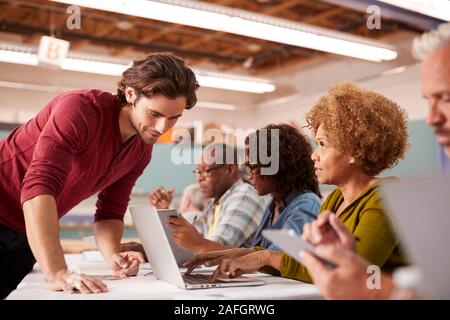 Teacher Helping Mature Woman Attending IT Class In Community Centre Stock Photo