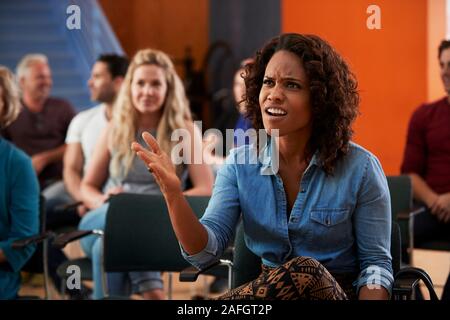 Frustrated Woman Asking Question At Group Neighborhood Meeting In Community Center Stock Photo