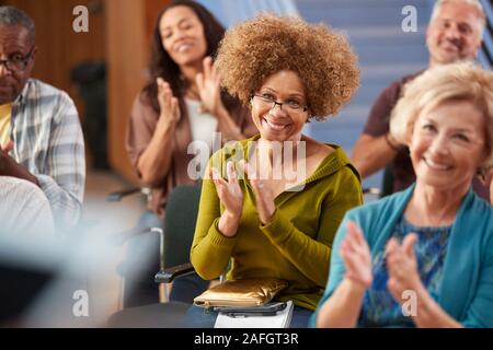 Group Attending Neighborhood Meeting Applauding Speaker In Community Center Stock Photo