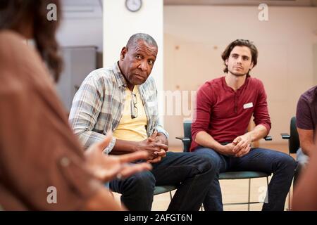 People Attending Self Help Therapy Group Meeting In Community Center Stock Photo