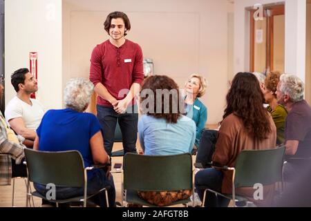 Man Standing To Address Self Help Therapy Group Meeting In Community Center Stock Photo