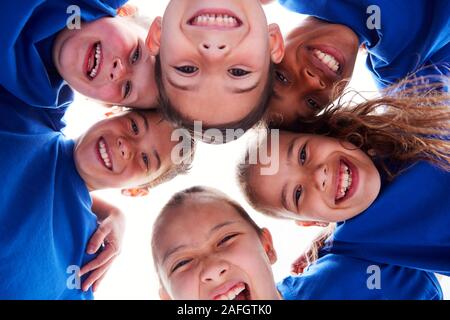 Low Angle View Looking Up Into Faces Of Children In Huddle On Sports Day Stock Photo