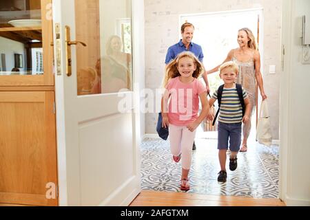 Family Returning Home From Shopping Trip Carrying Grocery Bags Stock Photo