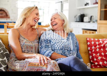 Smiling Mother With Adult Daughter Relaxing On Sofa At Home Stock Photo