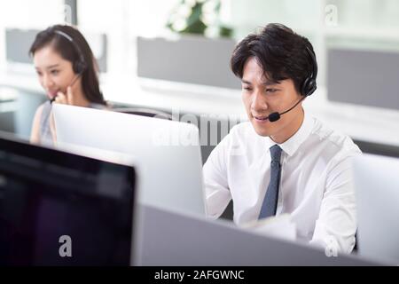 Young man working next to his colleague in call center Stock Photo