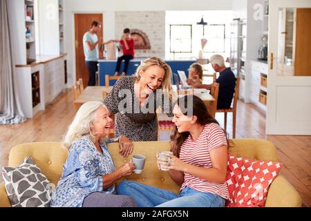 Mother With Adult Daughter And Teenage Granddaughter Relaxing On Sofa And Talking At Home Stock Photo