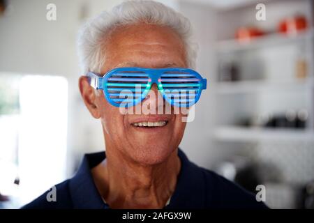 Senior Man At Home Wearing Novelty Party Glasses Stock Photo