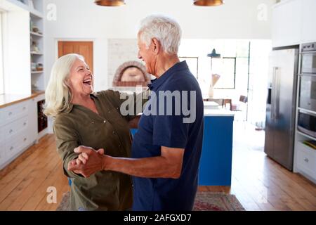 Senior Couple At Home Dancing In Kitchen Together Stock Photo