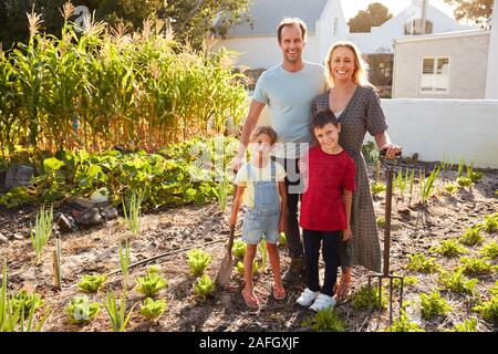 Portrait Of Children Helping Parents To Look After Vegetables On Allotment Stock Photo