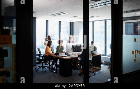 Creative business team working together in a casual office, seen through glass wall Stock Photo