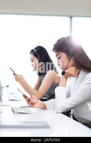 Young call center agents using smartphone in office Stock Photo