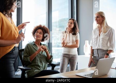 Four female colleagues in discussion at a desk in a creative office, three quarter length, close up Stock Photo