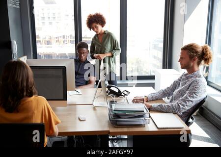 Young adult creatives working together at a desk in a casual office, close up Stock Photo