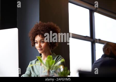 Millennial black female creative sitting at a desk in an office using a computer, close up Stock Photo