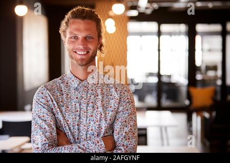 Millennial white male creative standing in an office with arms crossed, smiling to camera, waist up Stock Photo