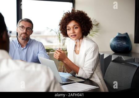 Millennial black businesswoman listening to colleagues at a corporate business meeting, close up Stock Photo