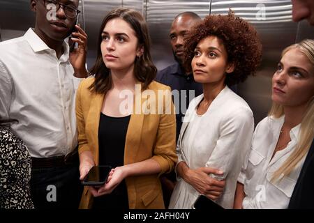 Work colleagues standing in an elevator at their office, close up Stock Photo