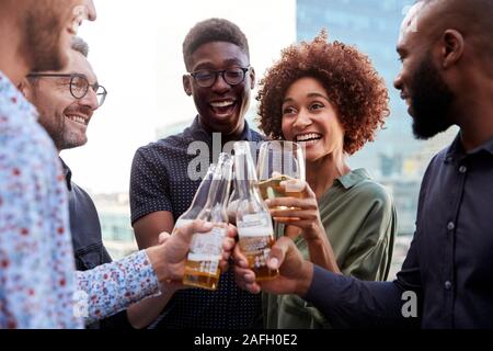 Happy creative business colleagues having a drink after work raise glasses to make a toast Stock Photo