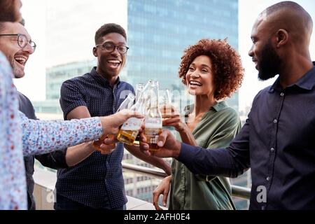 Smiling creative business colleagues drinking after work raising glasses to make a toast Stock Photo