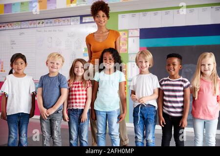 Portrait Of Elementary School Pupils Standing In Classroom With Female Teacher Stock Photo